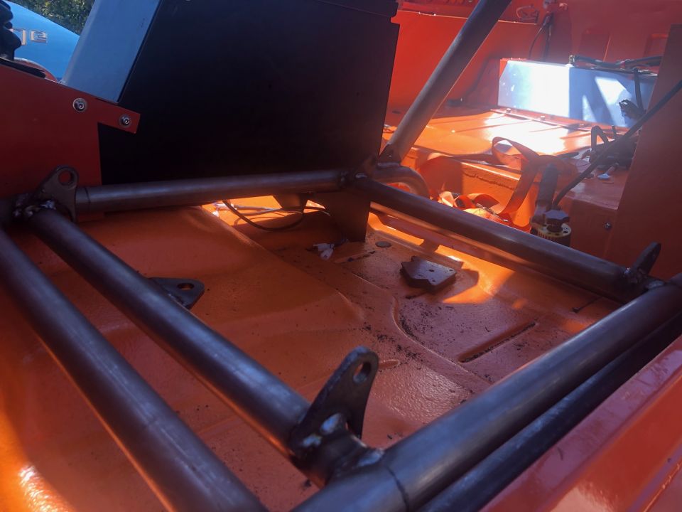 Interior of an orange vehicle with a custom roll cage and black box.