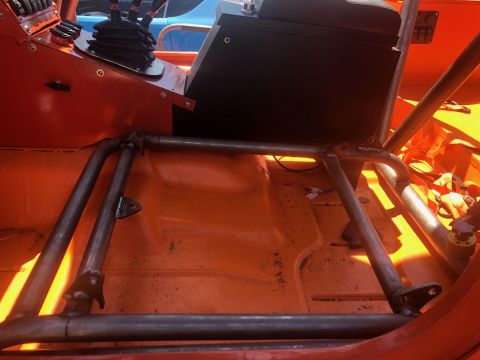 1992 Jeep Wrangler - The interior of an orange Jeep Wrangler features a roll cage, a center console with gear shifters, and a black box mounted behind the conso…