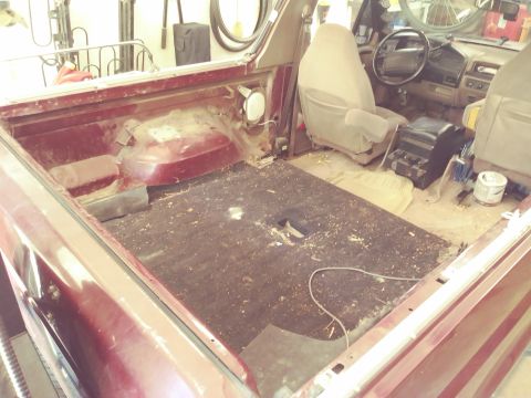1996 Ford Bronco - The interior and rear bed of a maroon Ford Bronco is shown, with the seats and dashboard visible. The vehicle appears to be undergoing some…