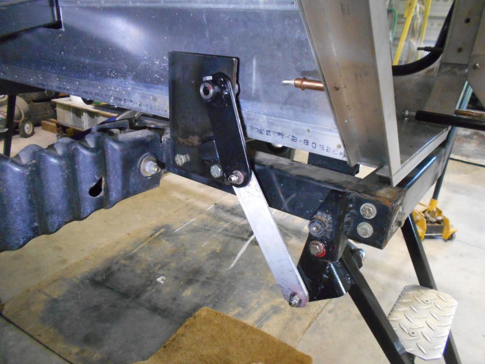 Close-up of vehicle linkage mechanism attached to black frame and ribbed component.