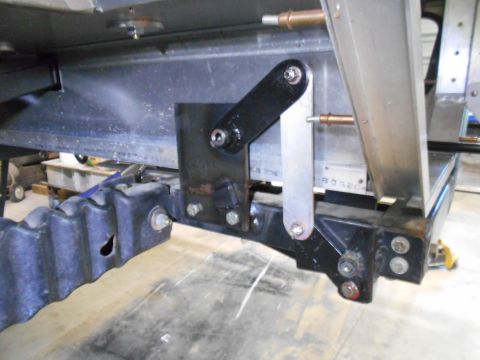 1992 Ford Bronco - A close-up view shows a black metal bracket assembly attached to the underside of a vehicle, featuring a pivoting arm and bolted connection…