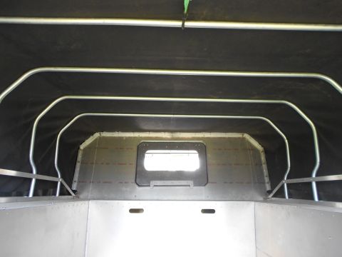 1992 Ford Bronco - Interior view of a custom aluminum and black fabric build, featuring a roll cage and a small window.