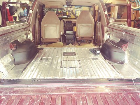 1996 Ford Bronco - The interior of a maroon Ford Bronco is shown with the rear cargo area stripped down and covered in sound deadening material. The front sea…