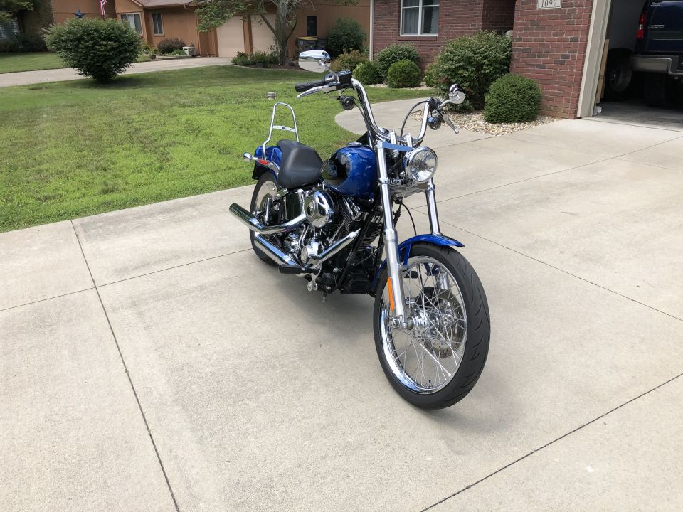 Blue Harley-Davidson motorcycle parked on a driveway in front of a house