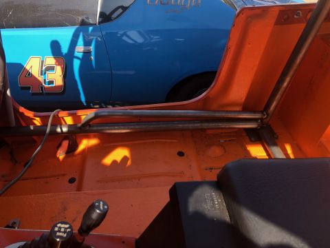 1992 Jeep Wrangler - The interior of an orange Jeep Wrangler shows a roll cage and a view of a blue Dodge muscle car with the number 43 on the door parked next…