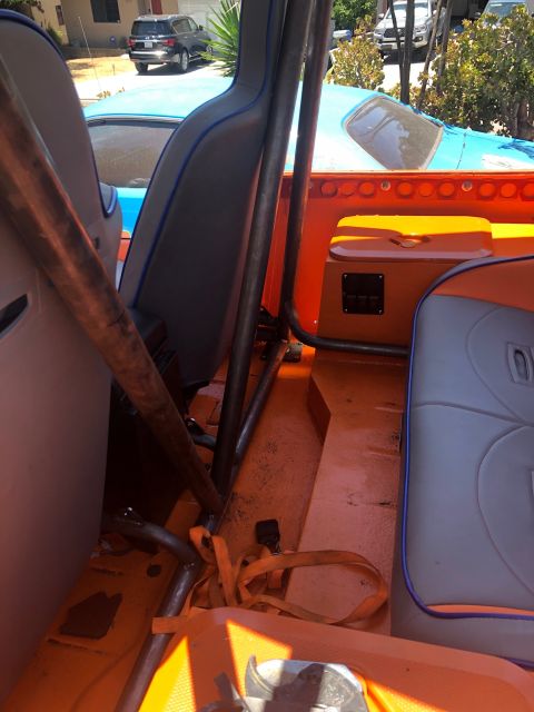 1992 Jeep Wrangler - The interior of a custom vehicle features orange flooring and accents, with grey seats trimmed in blue piping. A metal roll cage is visible…