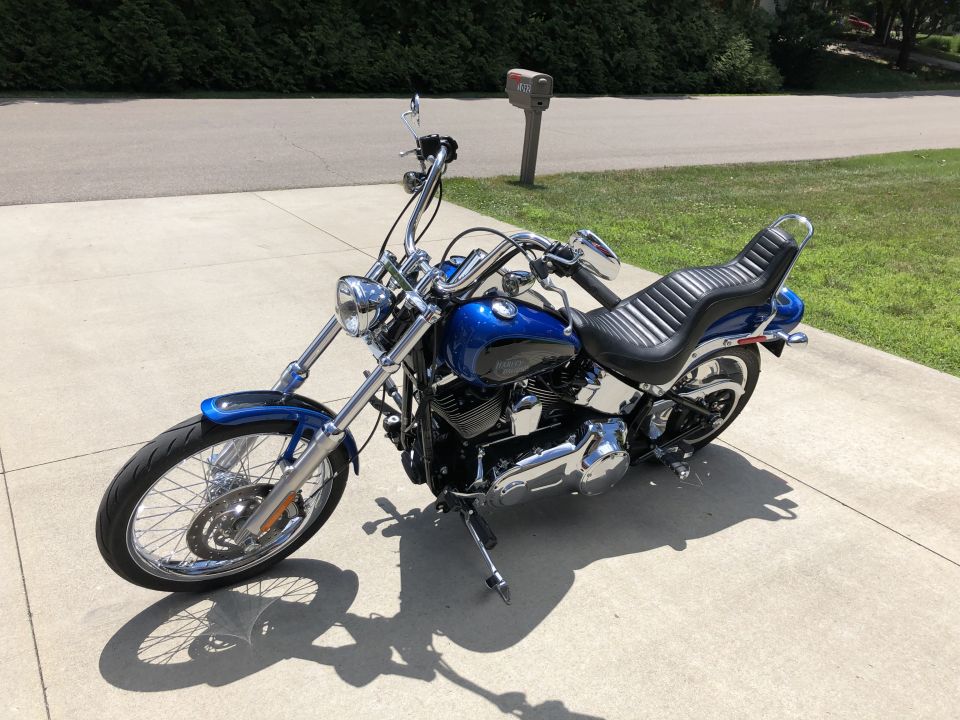 Blue and black Harley-Davidson Softail motorcycle parked on a concrete driveway.