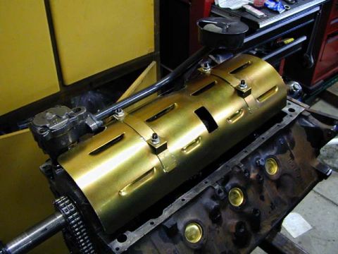 1979 Ford Bronco - A close-up view of an engine block with a gold colored cover and chain drive mechanism.