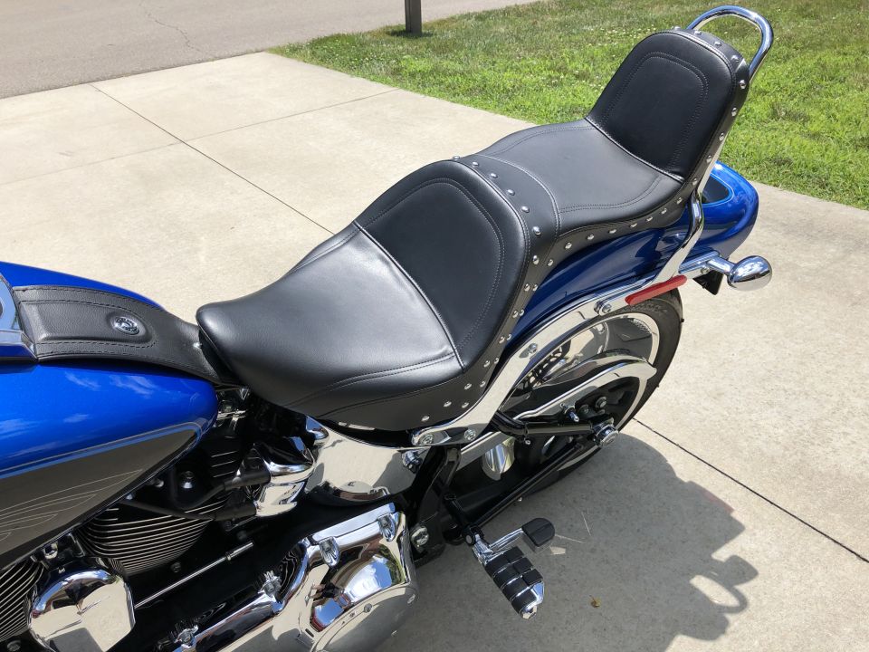 Blue Harley-Davidson Softail motorcycle with black studded seat and chrome details.