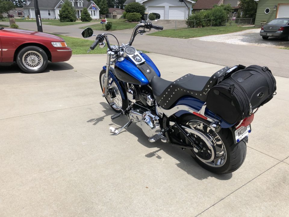 Blue and black Harley-Davidson Softail motorcycle with studded seat and saddlebag parked on driveway.