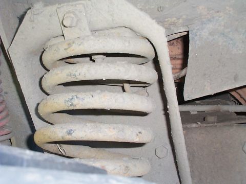 1979 Ford Bronco - Underside view of a vehicle's suspension coil spring and mounting hardware.