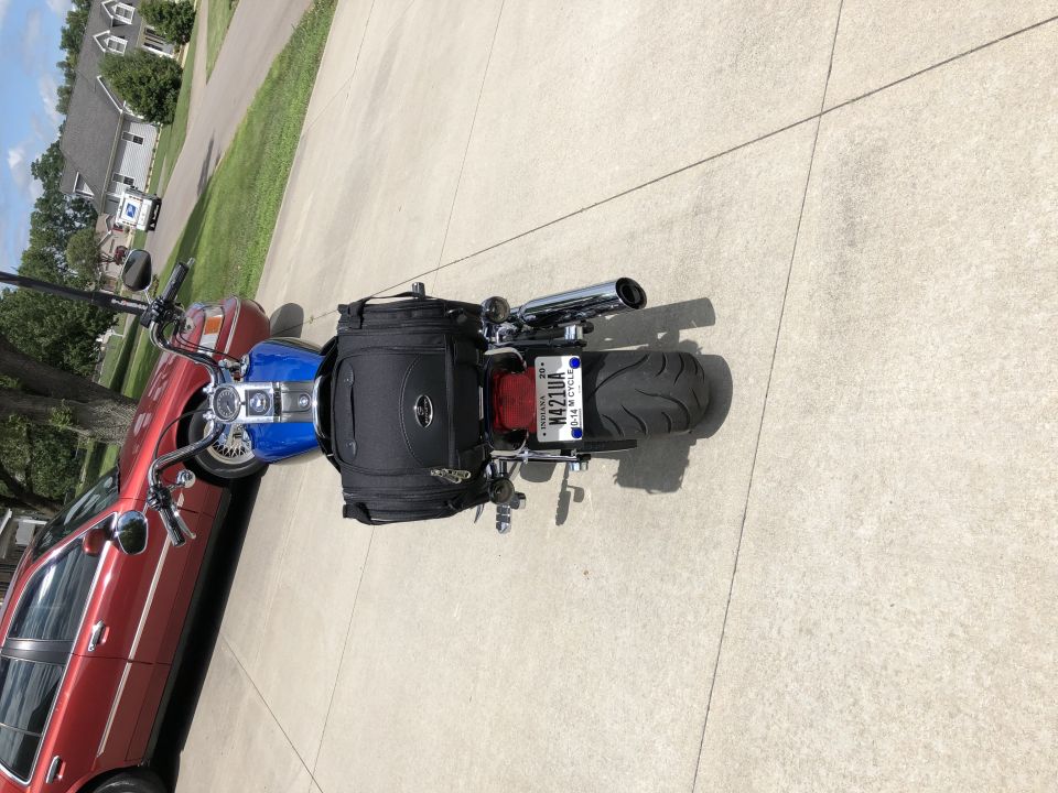 Blue Harley-Davidson Softail motorcycle with black saddlebag parked on concrete driveway.