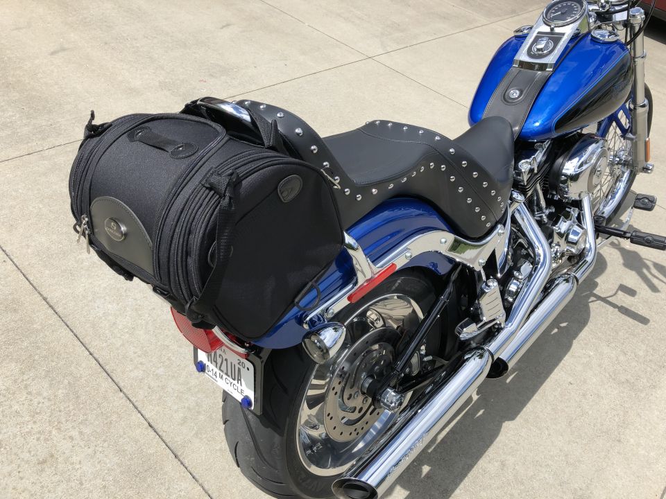 Blue and black Harley-Davidson motorcycle with black studded seat and saddlebag, parked on concrete.