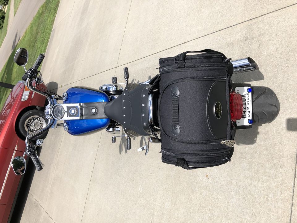 Blue and black Harley-Davidson motorcycle with a black tail bag parked on a driveway.