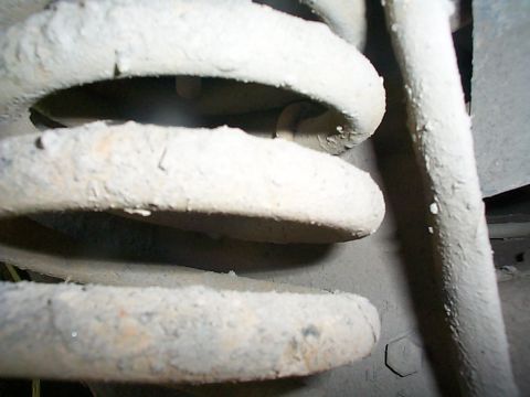 1979 Ford Bronco - A close-up view of a heavily corroded suspension coil spring, likely from a vehicle's undercarriage.