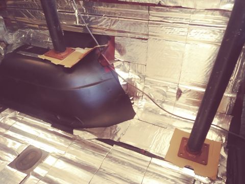 1996 Ford Bronco - The interior of a vehicle is being lined with reflective insulation. A dark-colored, curved metal component, possibly part of the undercarr…
