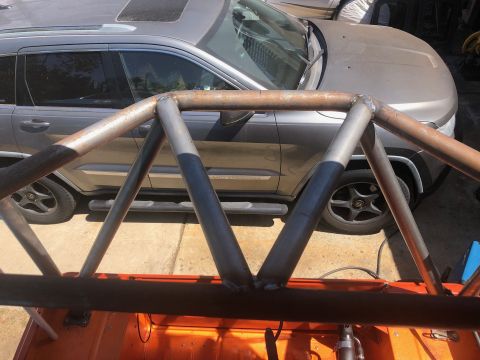 1992 Jeep Wrangler - A custom metal roll cage is visible in the foreground, with a silver SUV parked behind it.