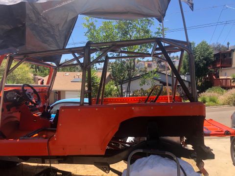 1992 Jeep Wrangler - An orange Jeep Wrangler is partially visible with a custom roll cage installed.