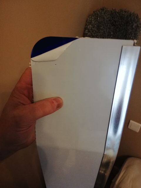 1996 Ford Bronco - A hand holds a white vehicle trim piece with a blue accent and a chrome strip, possibly being replaced or inspected.