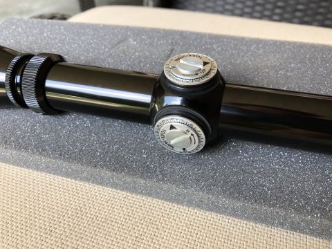 1995 Mercury Grand Marquis - Close-up of a black rifle scope, showing its adjustment turrets and textured rings.