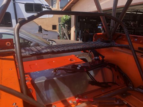 1992 Jeep Wrangler - Interior view of an orange vehicle with a custom roll cage and metal mesh shelf, showing visible wiring.
