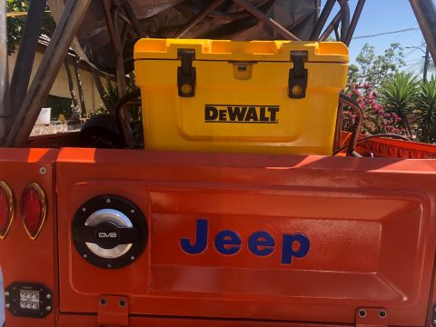 1992 Jeep Wrangler - A yellow DeWalt cooler is secured to the back of an orange Jeep, with the brand name visible on both.