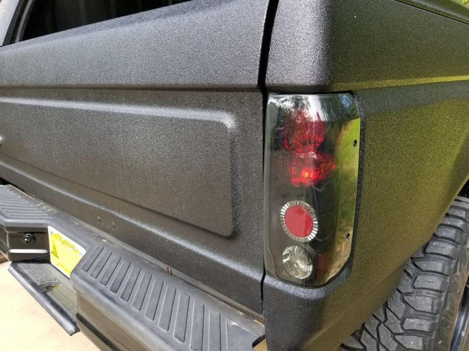 Black textured rear quarter panel and taillight assembly of a truck