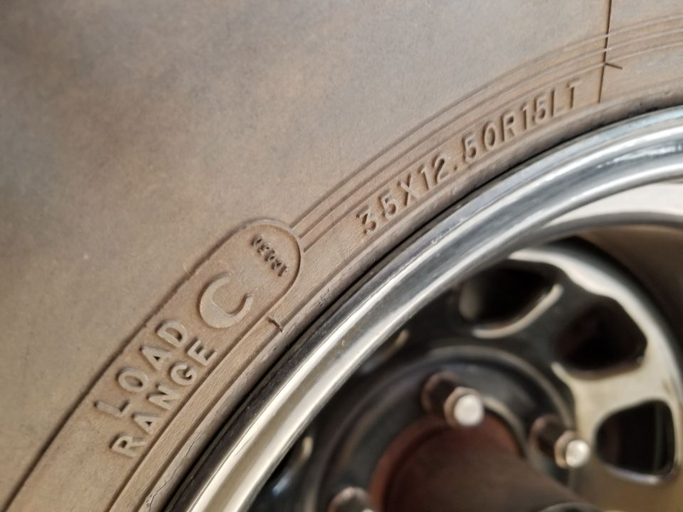 Close-up of a tire with size 35x12.50R15LT and Load Range C, mounted on a chrome rim