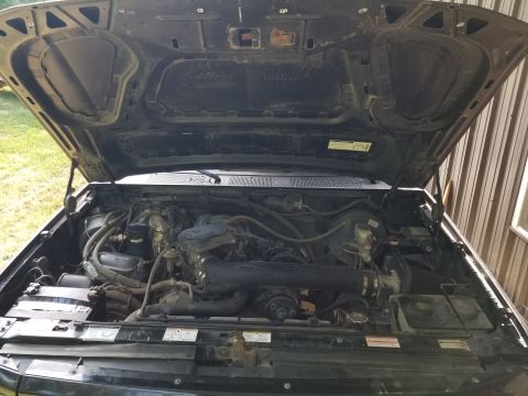 1996 Ford Bronco - The engine bay of a black vehicle is shown with the hood open, revealing the engine components.