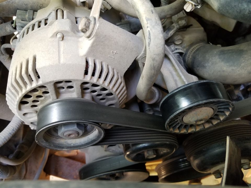 Alternator with serpentine belt wrapped around pulleys and tensioner