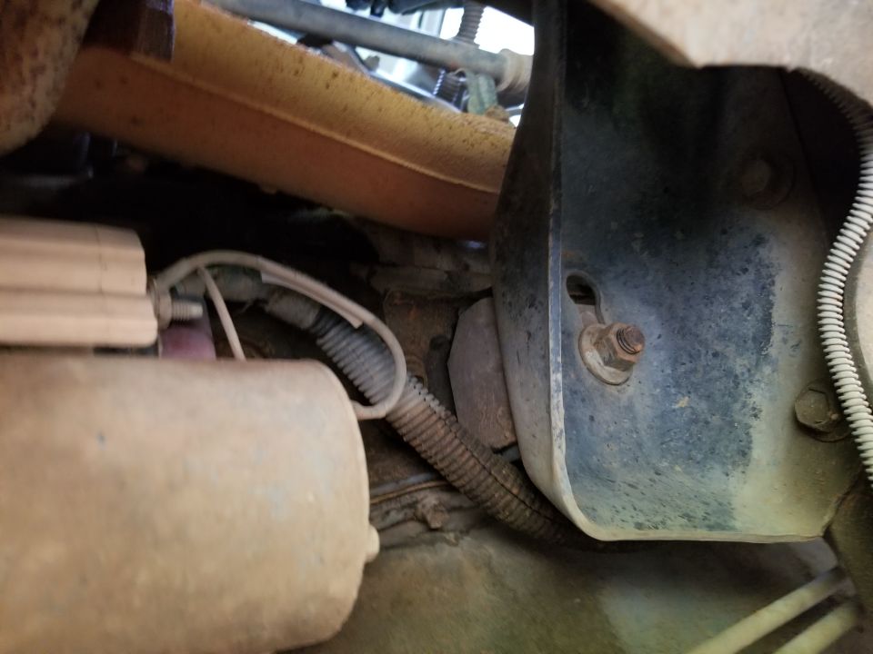 Close-up of engine bay with yellow exhaust manifold, wiring, and metal bracket