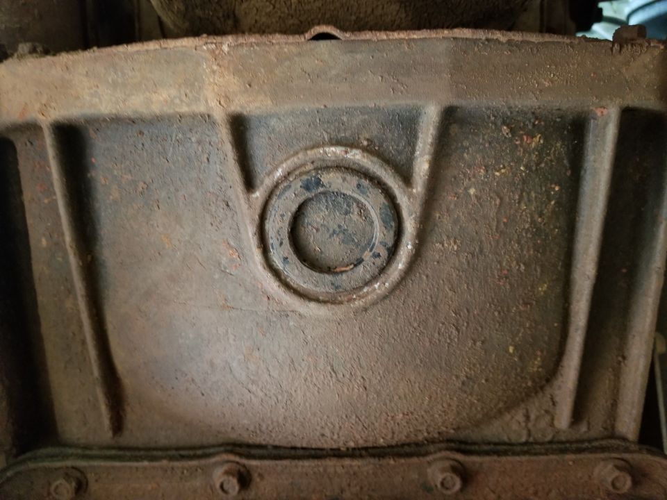 Close-up of a rusty, cast iron transmission case with a circular recess