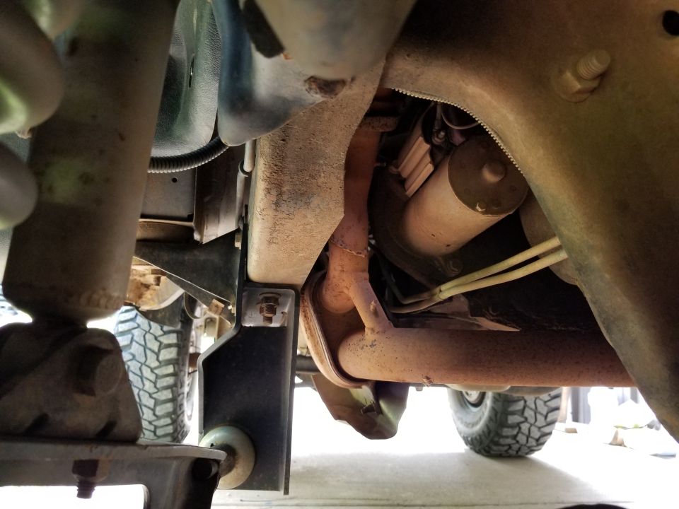 Underside view of a vehicle showing exhaust pipe, suspension parts, and a starter motor