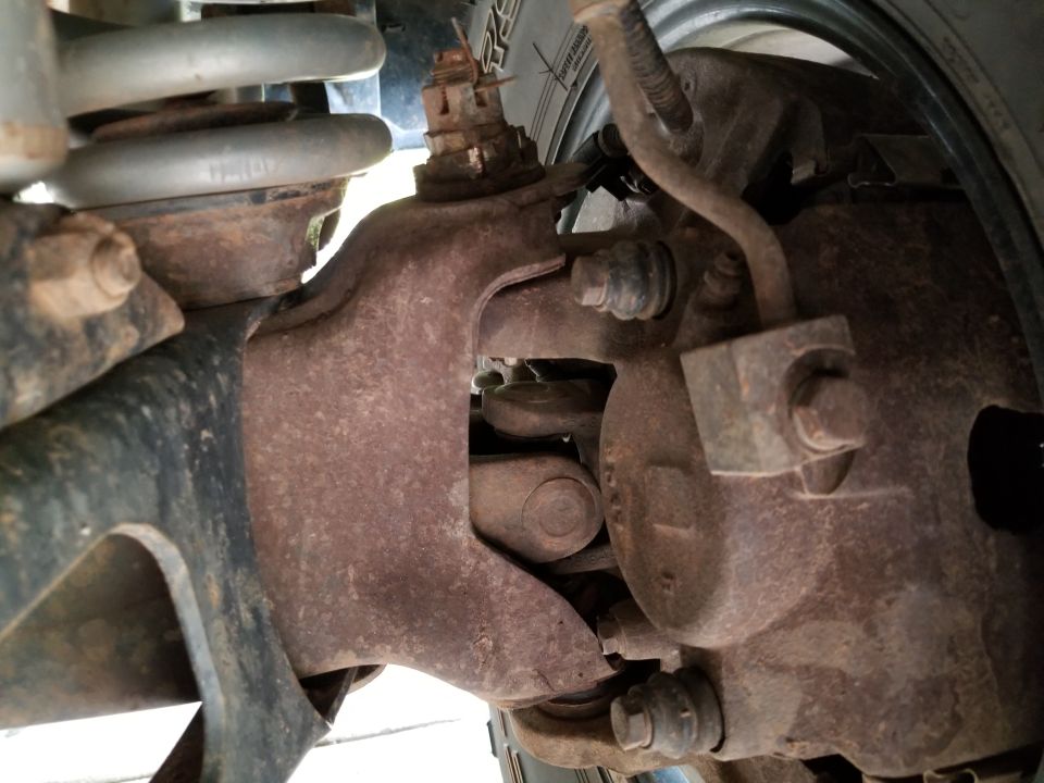 Close-up of a heavily rusted suspension component, likely from a truck or SUV