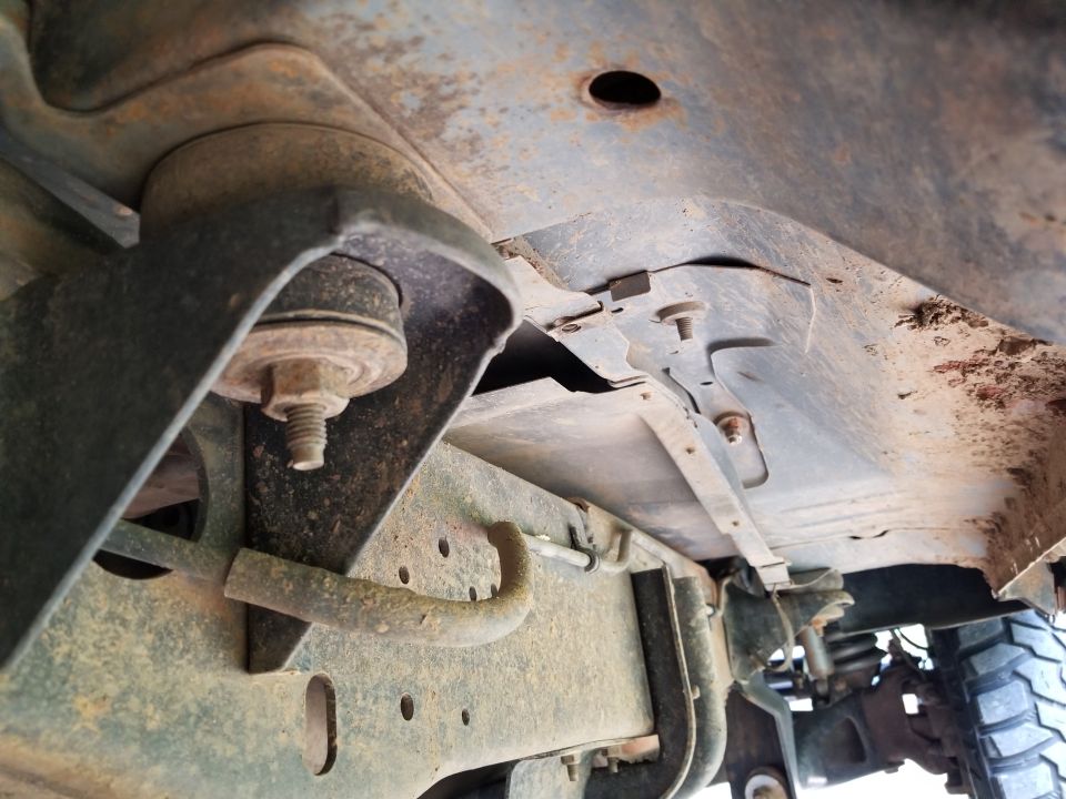 Close-up of rusty vehicle frame with suspension mount and rubber bushing
