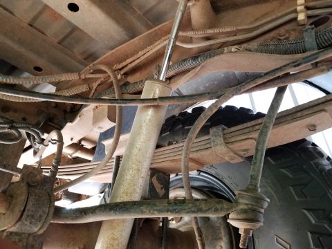 1996 Ford Bronco - Close-up of the rear suspension system, showing leaf springs, shock absorber, and brake lines.