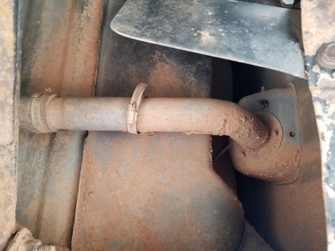 1996 Ford Bronco - Close-up of a dirty exhaust pipe with hose clamps, indicating a section of a vehicle's undercarriage.