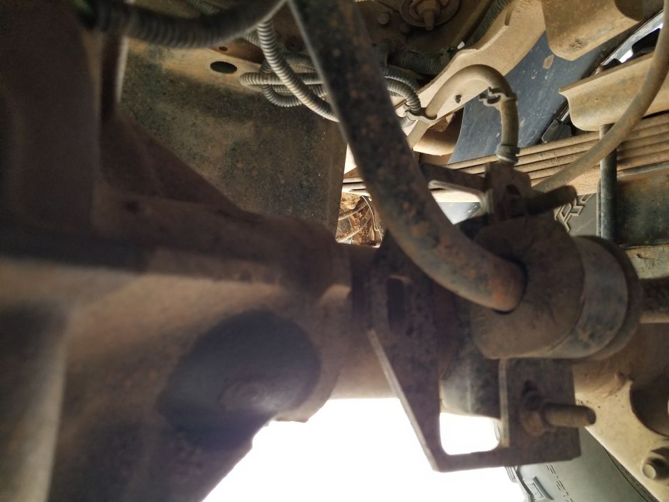 Close-up of a vehicle's rear axle and suspension, showing brake lines and leaf springs