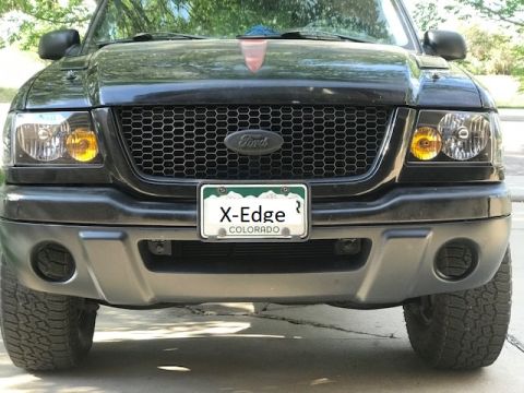 2000 Ford Explorer - Front view of a black Ford truck a honeycomb grille and a custom Colorado license plate reading 'X-Edge'.