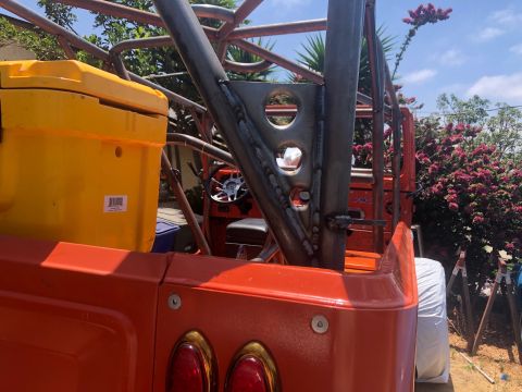 1992 Jeep Wrangler - The rear of an orange vehicle is shown with a large yellow cooler and a custom-welded roll cage structure.