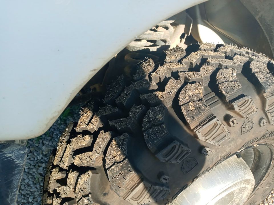 Close-up of a muddy off-road tire with aggressive tread pattern