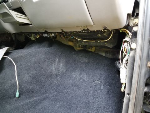 1996 Ford Bronco - Exposed wiring and carpet are visible under the dashboard of a vehicle.