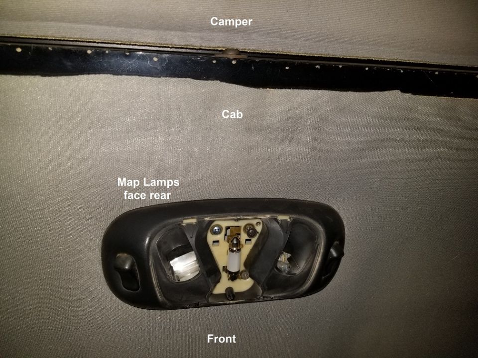 Overhead map light assembly removed from vehicle interior, showing bulb sockets and wiring
