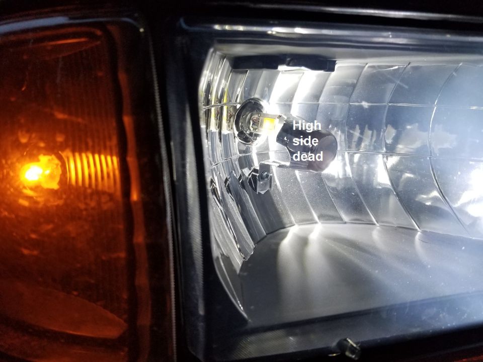Close-up of a car headlight showing a burnt-out high beam bulb labeled 'High side dead'. The amber turn signal is visible on the left