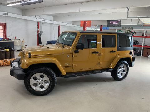2009 Harley-Davidson FLH - This is a yellow Jeep Wrangler with a black hardtop, seen from the side in a garage.
