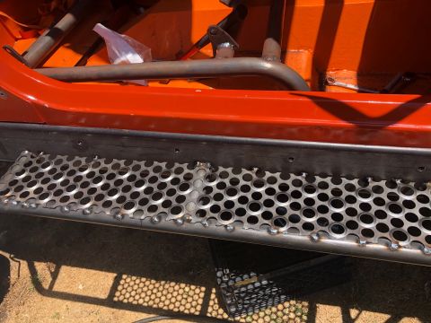 1992 Jeep Wrangler - Custom rock sliders and roll cage detail on an orange vehicle.