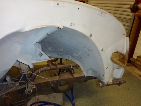 1969 MINI Cooper - Unidentified vehicle's wheel well and suspension components are visible, undergoing restoration.