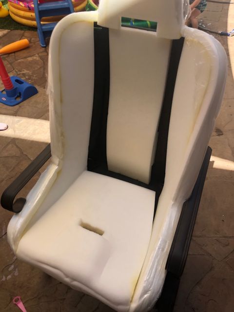 1992 Jeep Wrangler - The foam padding of a car seat is visible, with black seatbelt straps integrated into the design.