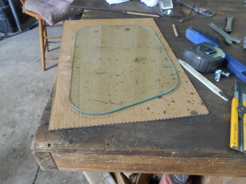 1992 Ford Bronco - A glass pane is placed on a cardboard template, surrounded by various tools on a workbench.