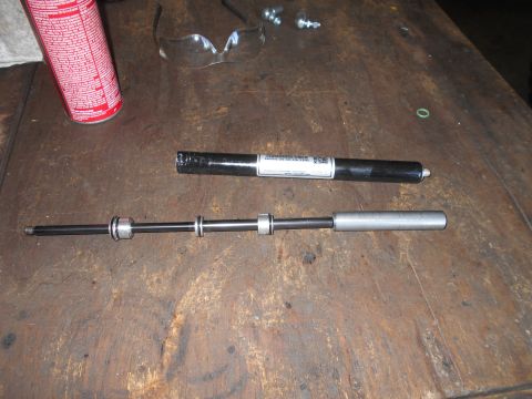 1992 Ford Bronco - Disassembled shock absorber components and a can of spray are laid out on a weathered wooden surface.